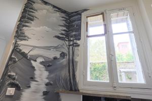 a wall with a mural of a tree and a window at Studio Alésia - HALA PARIS in Paris