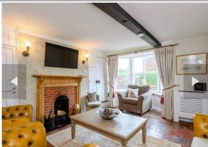 a living room with a fireplace and a tv at West Cottage. Central, beautiful, 2 mins to beach. in Cromer