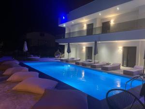 a swimming pool with chairs and a building at night at V luxury Suites in Pefkohori
