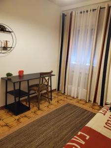 una mesa y una silla en una habitación con ventana en Rioja Martín, en Alba de Tormes