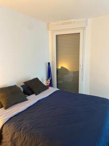 Un dormitorio con una gran cama azul y una ventana en Le Denecourt - à deux pas de la Gare et de la Forêt de Fontainebleau, en Avon