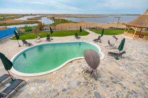 a swimming pool with chairs and a gazebo at Pensiunea Dolosman in Jurilovca