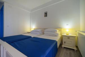 a bedroom with a bed with blue sheets and pillows at Pensiunea Dolosman in Jurilovca +52 photos