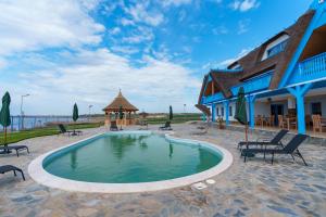 a swimming pool in front of a building with a house at Pensiunea Dolosman in Jurilovca