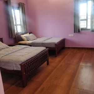 3 camas num quarto com paredes roxas e pisos em madeira em NanDha Illam- The Courtyard Heritage HomeStay em Yelagiri