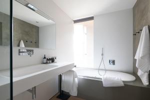 uma casa de banho branca com uma banheira e um lavatório em Ansitz Montani Eppan em Appiano sulla Strada del Vino