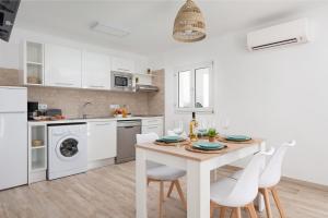 a white kitchen with a wooden table and white appliances at NEW! Apartment ONA 2 with Pool, AC, BBQ, Wifi in Cala D'or, Mallorca in Cala D'or