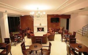 a living room with tables and chairs and a fireplace at Hotel Athina in Kato Loutraki