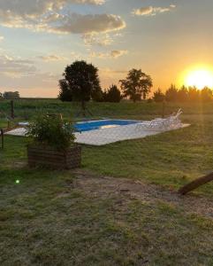 een zwembad in een veld met de zonsondergang op de achtergrond bij Casa de campo San Agustín in Tandil