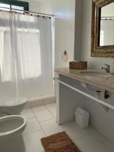 a bathroom with a toilet and a sink and a mirror at Casa de campo San Agustín in Tandil