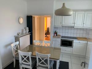 a kitchen with a wooden table and white cabinets at De Lelie in Achel