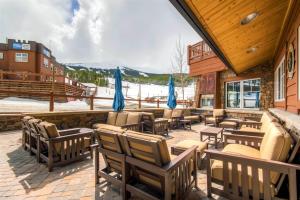 - une terrasse avec un bouquet de chaises et de parasols bleus dans l'établissement Luxury 3 Bedroom Ski In, Ski Out One Ski Hill Residence Located At The Base Of Peak 8 With Hot Tub Access, à Breckenridge