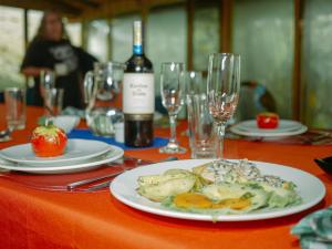 einen Tisch mit einem Teller Essen und einer Flasche Wein in der Unterkunft Birdwatchers House y Lodge in Mindo
