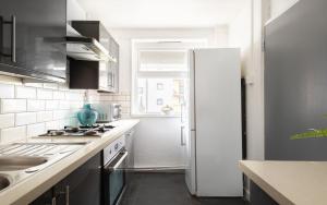 cocina blanca con nevera y fregadero en Spacious and Modern 4 Bed Apartment next to Borough Station, en Londres