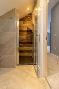 uma cabina de duche ao nível do chão num quarto com paredes de madeira em Spindrift em Abersoch