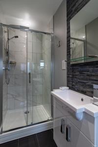 a bathroom with a glass shower and a sink at Spindrift in Abersoch