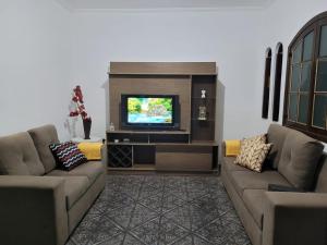 a living room with two couches and a television at Casa Grande para Família e Amigos in São Lourenço