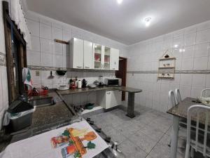 a kitchen with white tiled walls and white cabinets at Casa Grande para Família e Amigos in São Lourenço