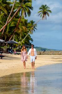 a man and a woman walking on the beach at The Warwick Fiji in Korolevu