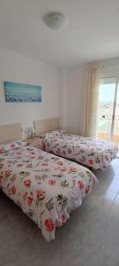 1 dormitorio con 2 camas con flores en Apartamento céntrico en la playa con piscina., en Peñíscola