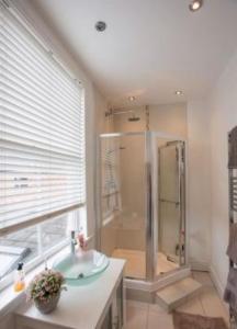 a bathroom with a shower and a sink and a tub at Beautiful 5 bedroom house in great location. in Spon End