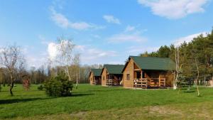 uma cabana de madeira com um telhado verde num campo em Świetny Spokój u Rybaków Uhnin 123 em Uhnin