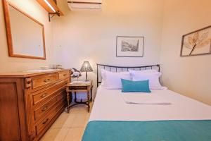 a bedroom with a bed with a dresser and a mirror at Villa Mariellie in Néa Péramos