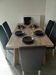 una mesa de madera con platos negros y copas de vino en City Comfort Apartment, en Preveza
