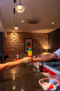 Dwie osoby trzymają drinka w barze. w obiekcie Coral Costa Caribe Beach Resort - All Inclusive w mieście Juan Dolio