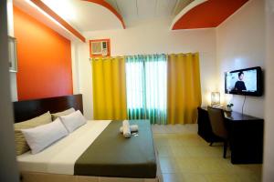 a bedroom with a bed and a desk and a television at First Pacific Inn Davao in Davao City