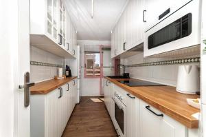 cocina con armarios blancos y microondas en MODERNO apartamento, 3 habitaciones, 1ª LINEA playa, GARAJE, en Calpe