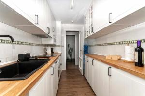 una cocina con armarios blancos y fregadero negro en MODERNO apartamento, 3 habitaciones, 1ª LINEA playa, GARAJE, en Calpe