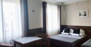 Cette chambre comprend 2 lits, une table et une fenêtre. dans l'établissement Pokoje Gościnne Nad Cukiernią w centrum miejscowości., à Jastarnia