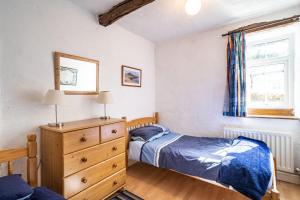 LindaleにあるCragg Cottageのベッドルーム1室(ベッド2台、ドレッサー、窓付)