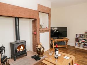 a living room with a wood stove and a tv at The Old Bothy in Wigton