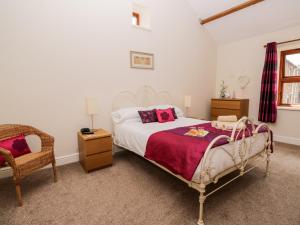 a bedroom with a large bed and a chair at The Old Bothy in Wigton