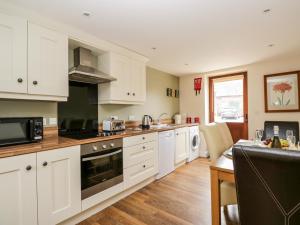 a kitchen with white cabinets and a counter top at The Old Grainstore in Wigton