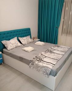 een bed met een blauw hoofdeinde in een kamer bij Apartament Katy Neversea in Constanţa