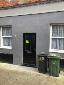 a black door and two trash cans in front of a building at 96 High Street in Ryde