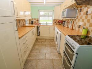 a kitchen with white cabinets and a stove top oven at Tir Bedw in Ederyn