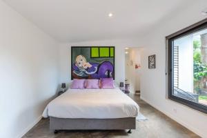 a bedroom with a bed with a painting on the wall at THE VILLA BY THE SEA Nouvelle-Caledonie in Mont-Dore +37 photos