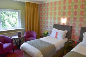 a hotel room with a bed and two chairs at The Lincoln Hotel in Lincoln