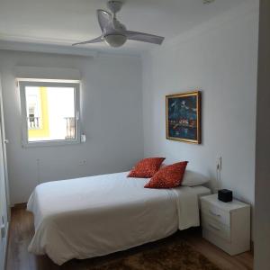 a bedroom with a bed with red pillows and a ceiling fan at Apartamento frente a la playa Piso 2 in Estepona