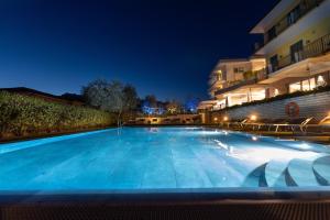 a large blue swimming pool at night at Wellness Hotel Casa Barca (Adult Only) in Malcesine