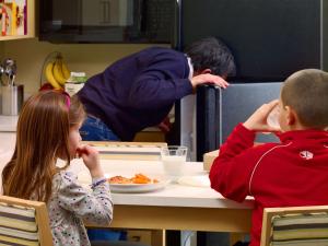 un chico y una chica sentados en una mesa comiendo comida en Avia Residences on Research - Extended Stay, en Westborough