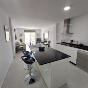 a kitchen with a black counter and stools in it at Apartamento frente a la playa Piso 3 in Estepona