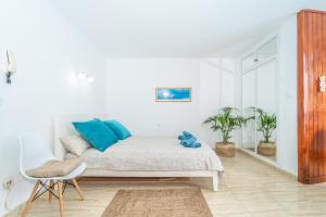 Cette chambre blanche dispose d'un lit avec des oreillers bleus. dans l'établissement Seaside apartment, à Punta del Hidalgo