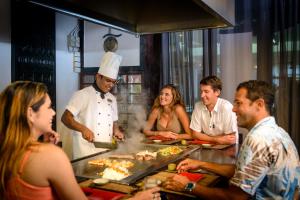 a group of people standing around a chef preparing food at The Warwick Fiji in Korolevu