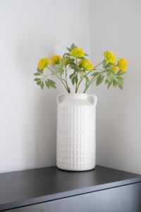 a white vase with yellow flowers in it on a table at Cannock 3 bedroom house - perfect for work or leisure in Great Wyrley