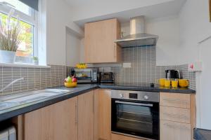 cocina con fregadero y fogones horno superior en Cannock 3 bedroom house - perfect for work or leisure en Great Wyrley